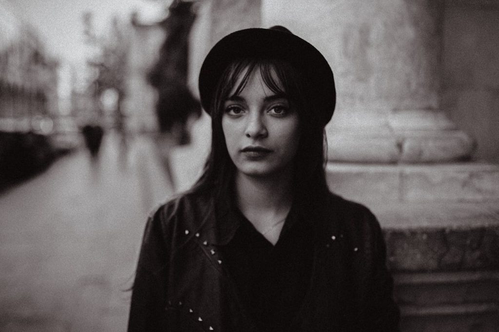 Black and white portrait of a woman in a vintage hat, exuding a moody and classic vibe.